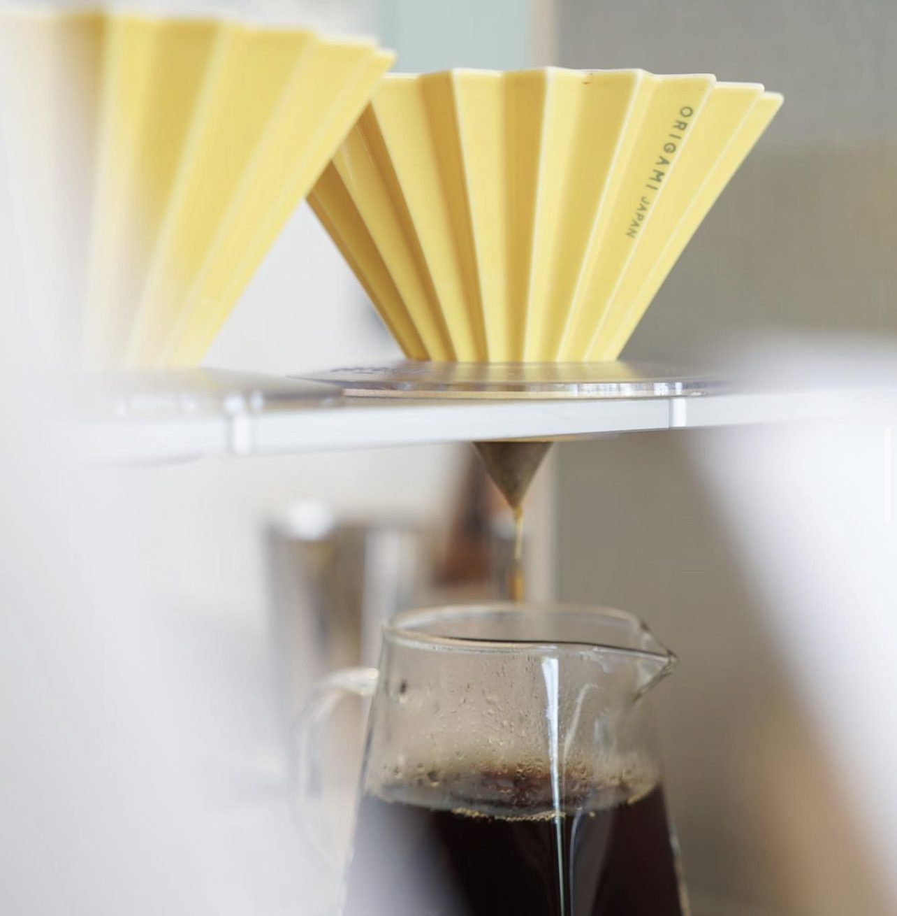 Origami dripper brewing into a glass server on a brew stand